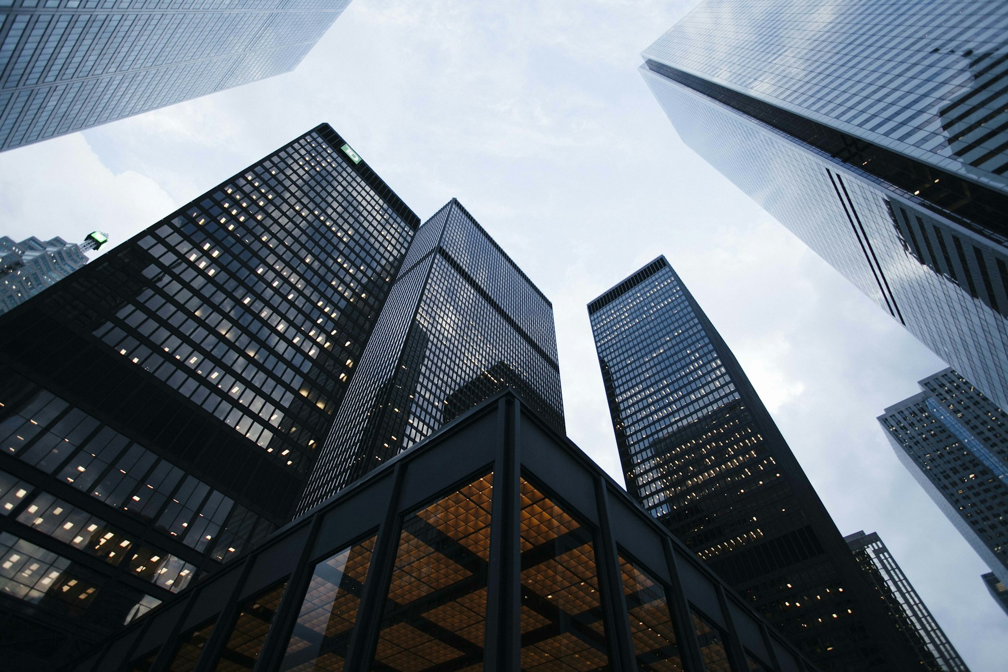 Generate an image of: Minimalist high-rise building facade, reflective glass and stark concrete, low angle against sky, architectural prompt, high contrast, clean lines